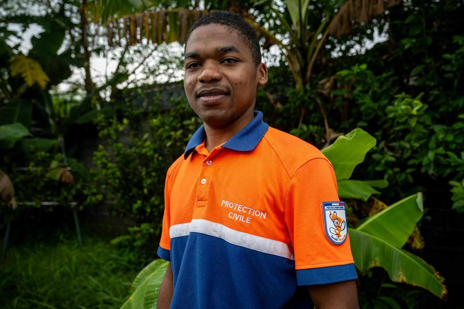 Un soignant de la Protection Civile Santé Mayotte, en polo de l’association, devant la végétation d’un centre de santé.